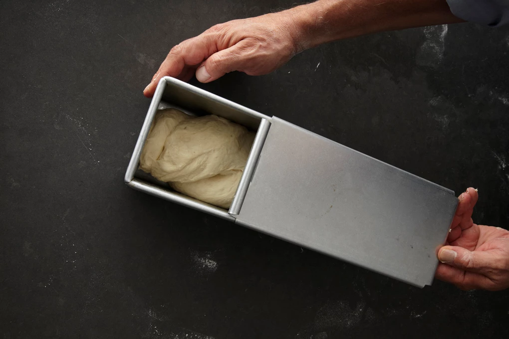 Partially opened Pullman Pan containing unproofed dough